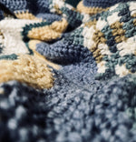 Load image into Gallery viewer, Close up photo of crochet blanket with wavy stripes of light blue, beige, brown, white, and turquoise. 
