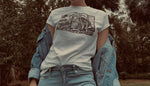 Load image into Gallery viewer, White t-shirt with black abstract wave design on model wearing blue jeans and jean jacket
