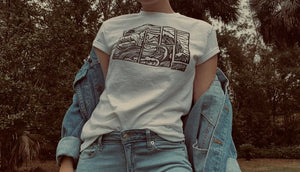 White t-shirt with black abstract wave design on model wearing blue jeans and jean jacket